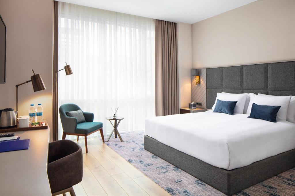 a hotel room with a large bed and a chair at Delta Hotels by Marriott Istanbul Vadi in Istanbul