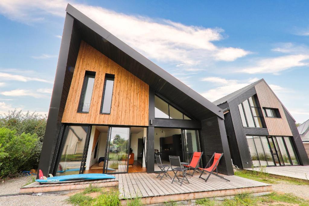 une maison noire avec des chaises rouges devant elle dans l'établissement À 300m de la plage, belle maison pour 5, à Sarzeau