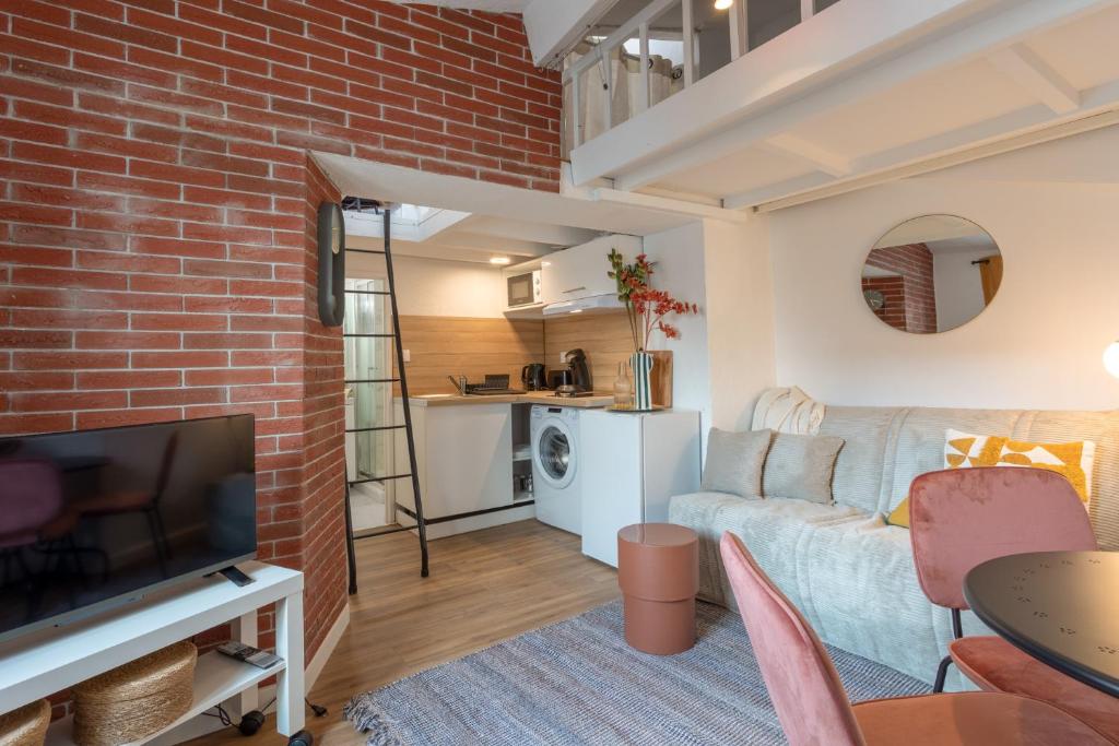 un salon avec un canapé et un mur de briques dans l'établissement Le Péri - Douillet appartement en Hypercentre, à Toulouse