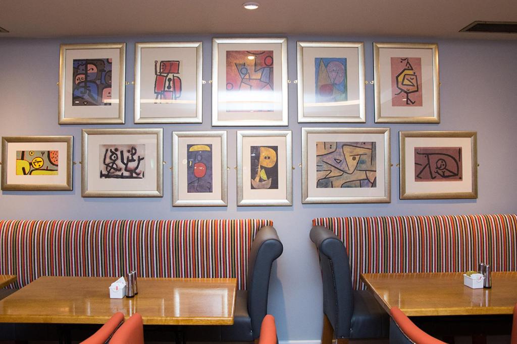 a restaurant with two tables and paintings on the wall at Davitts Guesthouse in Kenmare