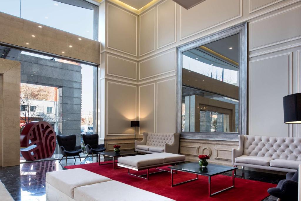 a living room with white furniture and a red rug at NH Collection Plaza Santiago in Santiago