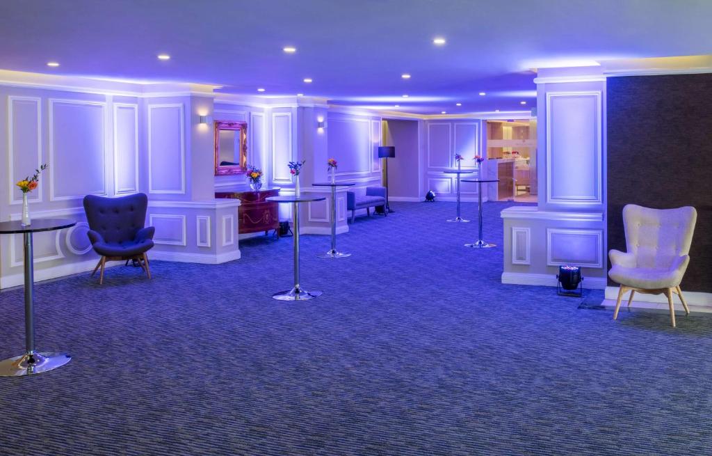 a room with chairs and tables and purple ceilings at NH Collection Plaza Santiago in Santiago