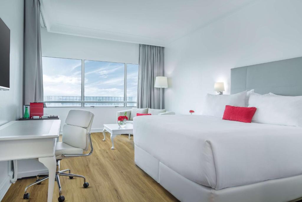 a white bedroom with a white desk and a bed at NH Collection Plaza Santiago in Santiago