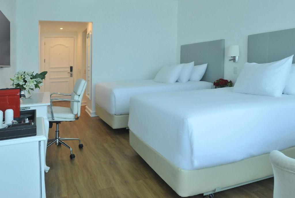a hotel room with two beds and a desk and a chair at NH Collection Plaza Santiago in Santiago