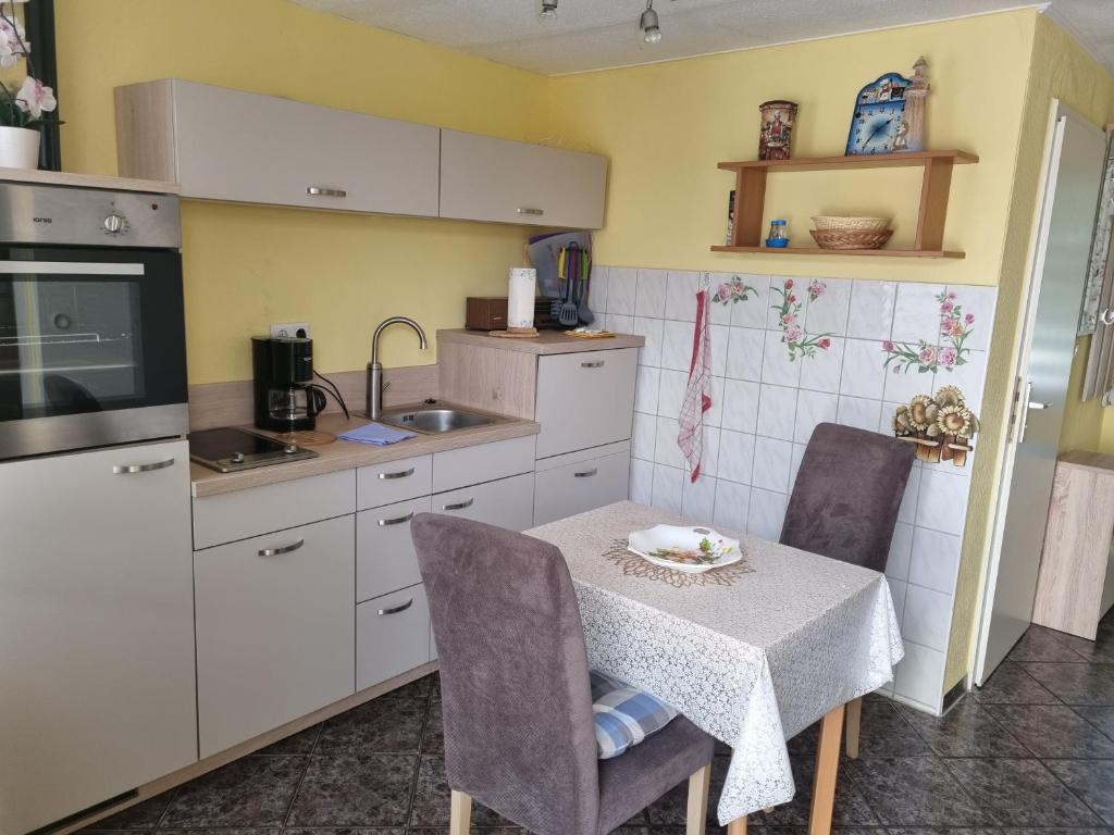 Una cocina con una mesa y sillas y un fregadero. en Bungalow Wiesenperle, en Trassenheide