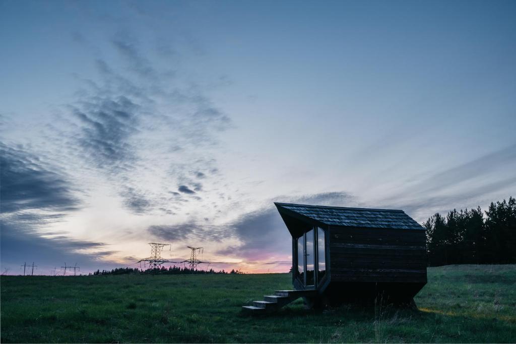 a smallshed in a field with a cloudy sky at Voose Päikesekodu seminari- ja puhkekeskus in Vose