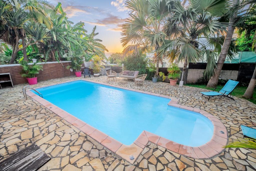 a swimming pool in a backyard with palm trees at La Kaz Isle Bourbon in Saint-Pierre
