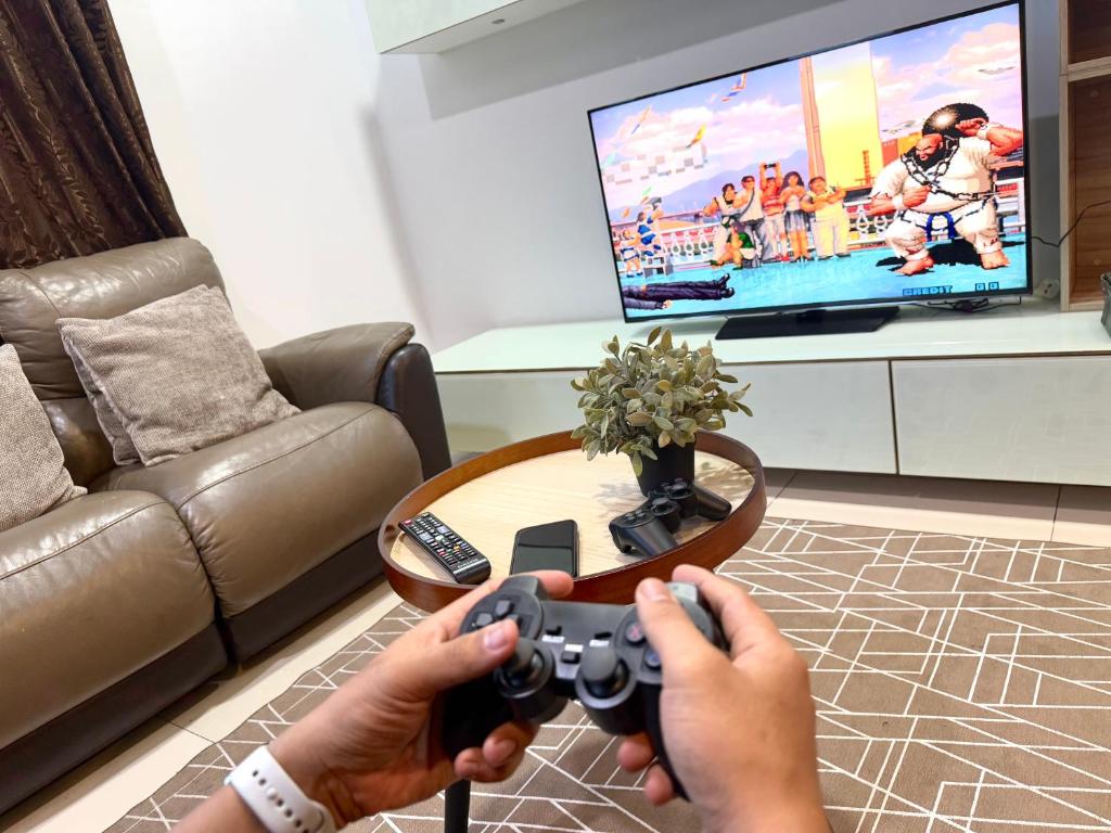 コタキナバルにあるS Homestay 2BR&2BR - Imago Kota Kinabaluのリビングルームにビデオゲームコントローラーを持つ者