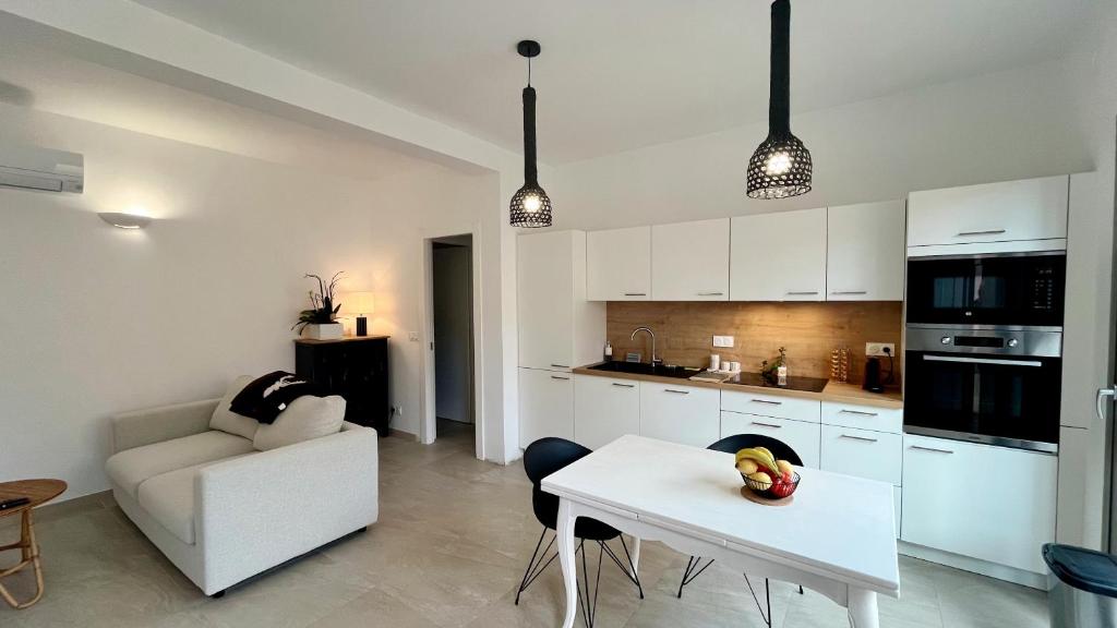 une cuisine avec des armoires blanches et une table dans une pièce dans l'établissement Appartement avec jardin proche de la mer, à Agay