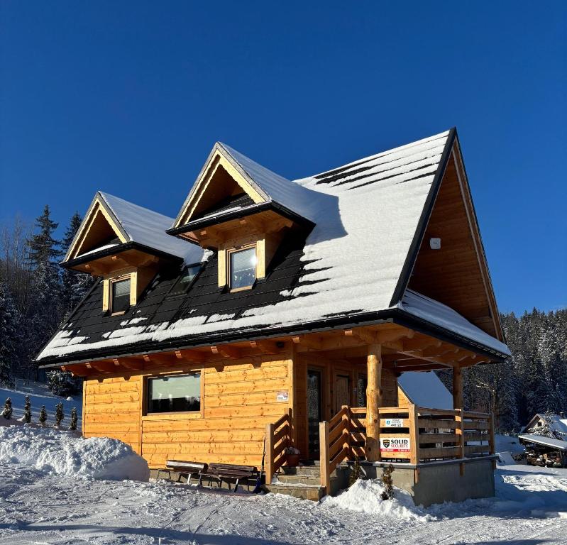 eine Blockhütte mit Schnee auf dem Dach in der Unterkunft Domek Zakopiański Widok in Zakopane