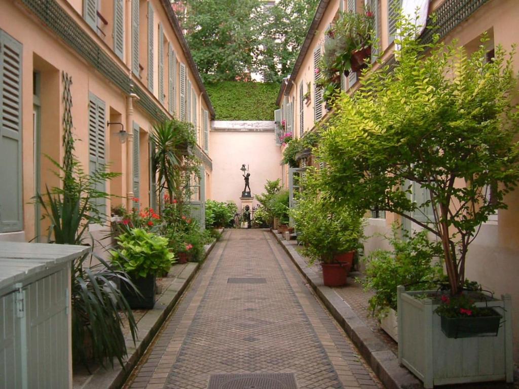 Une allée avec des plantes et une statue dans un bâtiment dans l'établissement Dupleix 75m2 sur cour arborée, à Paris
