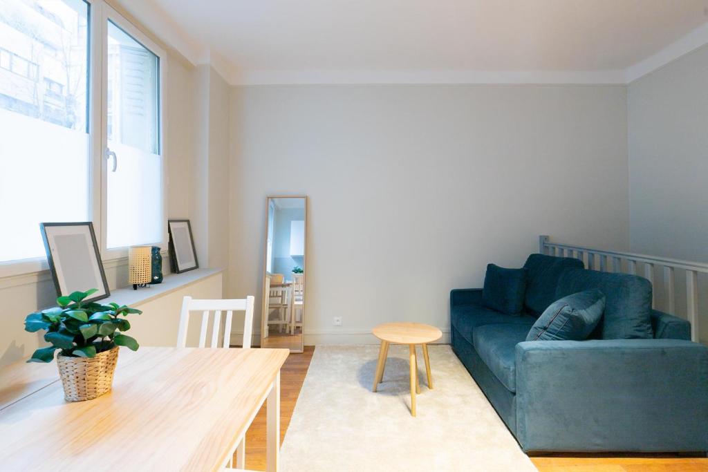 un salon avec un canapé bleu et une table dans l'établissement Majestic Suites - Paris 11, à Paris