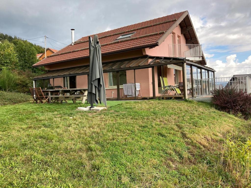 une maison avec un parasol dans l'herbe dans l'établissement Aux balcons des xettes, à Gérardmer