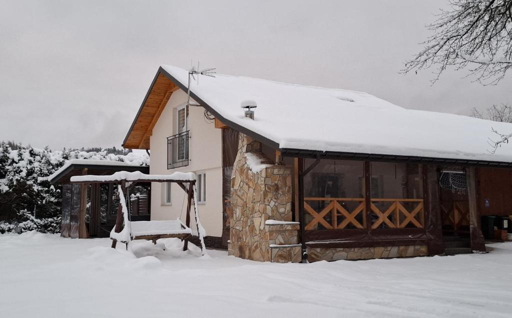 Una cabaña con nieve en el techo. en Apartamenty u Rudej, en Olszanica