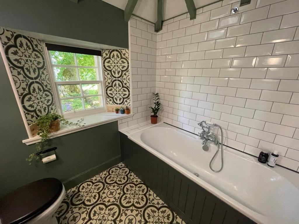 a bathroom with a tub and a toilet and a window at Gorgeous boutique off-grid cottage near Peebles in Peebles