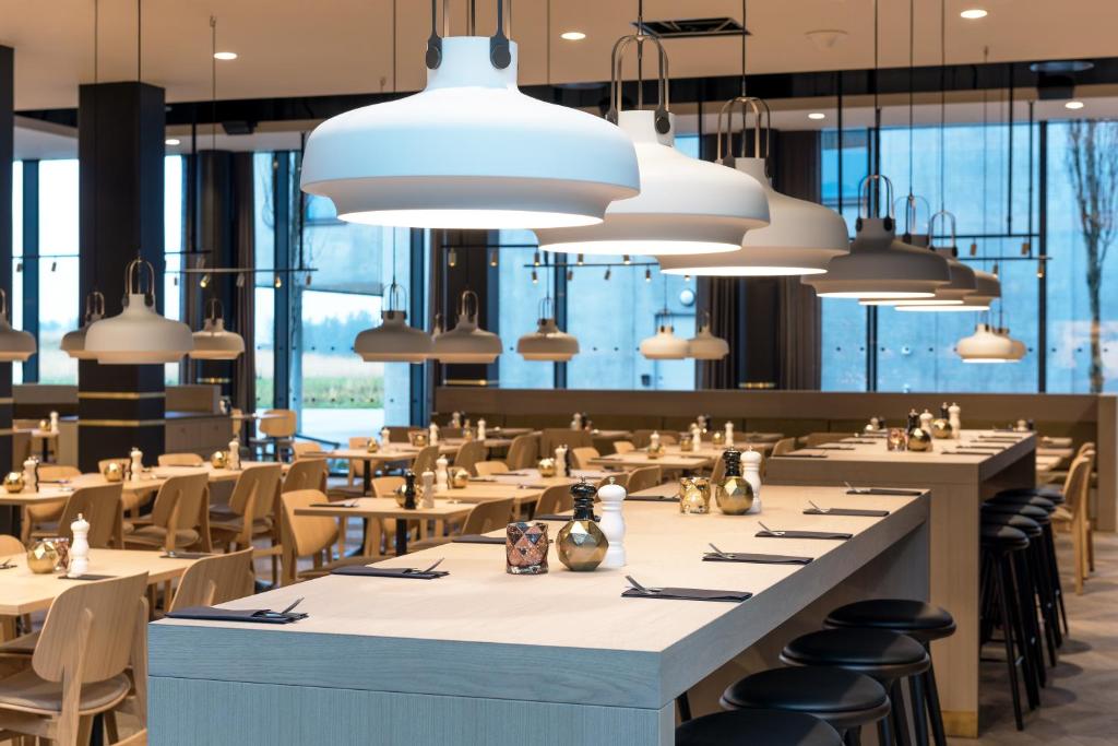 a restaurant with tables and chairs and large windows at Clarion Hotel Air in Sola