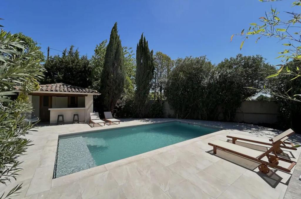 - une piscine dans un jardin avec 2 chaises et une table dans l'établissement Villa contemporaine et minimaliste, aux Angles (Gard)