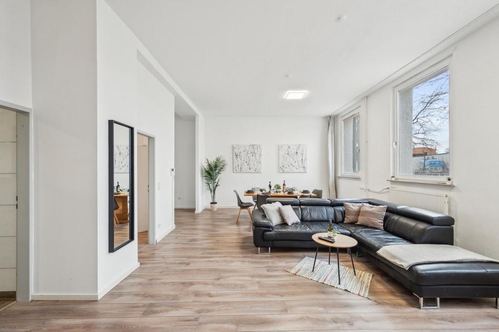 a living room with a black leather couch and a table at Yello Homes - Loft - Airport & Messe 6 Betten & Wifi in Nürnberg