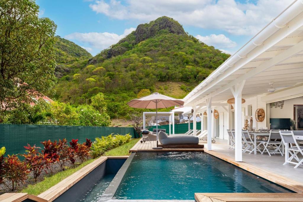 a house with a swimming pool with mountains in the background at Villa Bohème in Terre-de-Haut