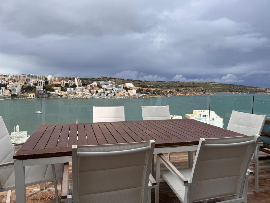a wooden table and chairs with a view of the water at Mare Amore in St. Paul's Bay