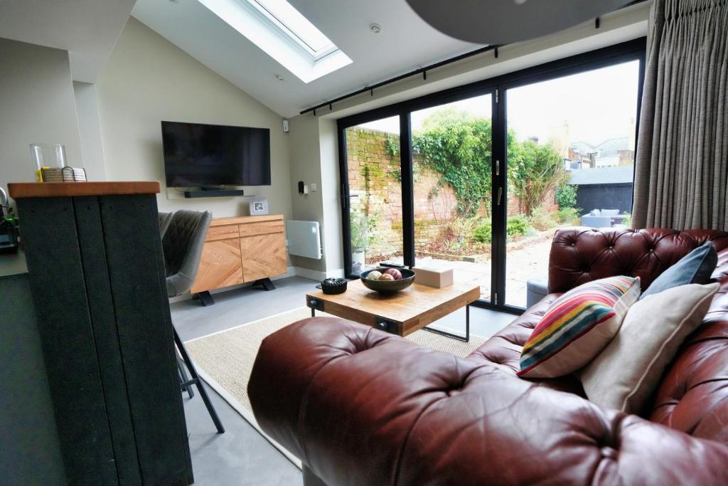 a living room with a leather couch and a television at Historic Tring 2 Story Flat on High Street in Tring