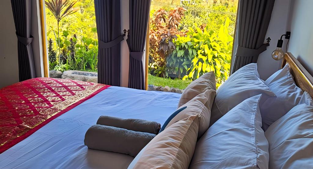 a bed in a room with a large window at Little Munduk, full private villa in Munduk