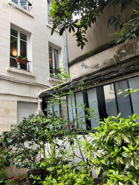 un bâtiment avec des fenêtres et des plantes devant lui dans l'établissement Le Cosy Parisien - Canal Saint Martin - Paris 10eme, à Paris