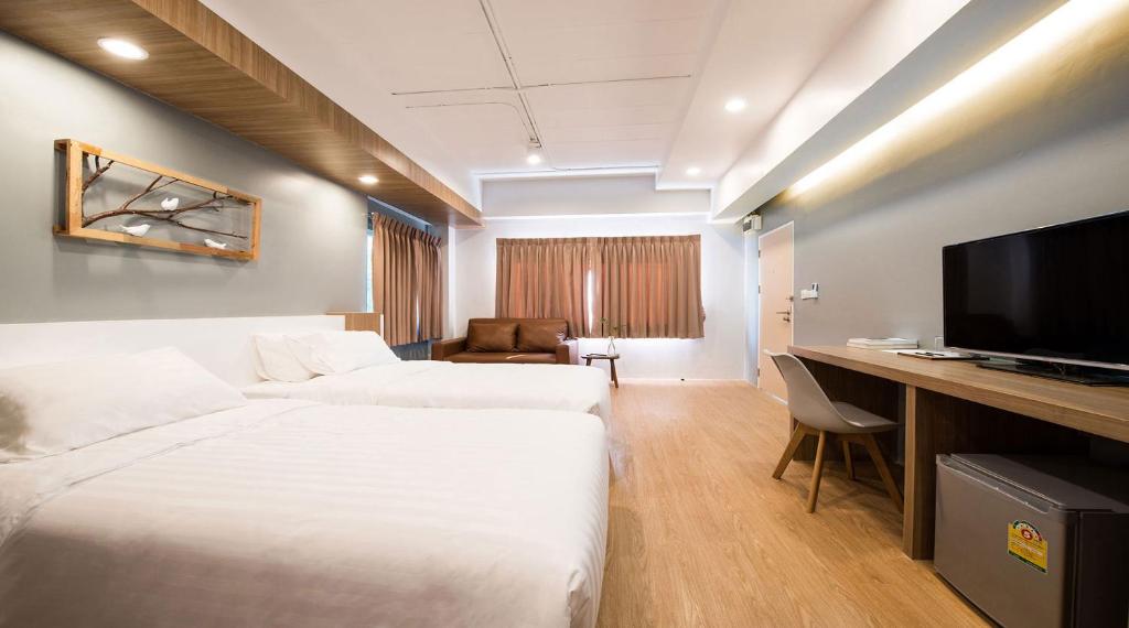 Habitación de hotel con 2 camas y escritorio con TV. en Shade House - Bitec Bangna, en Bangkok