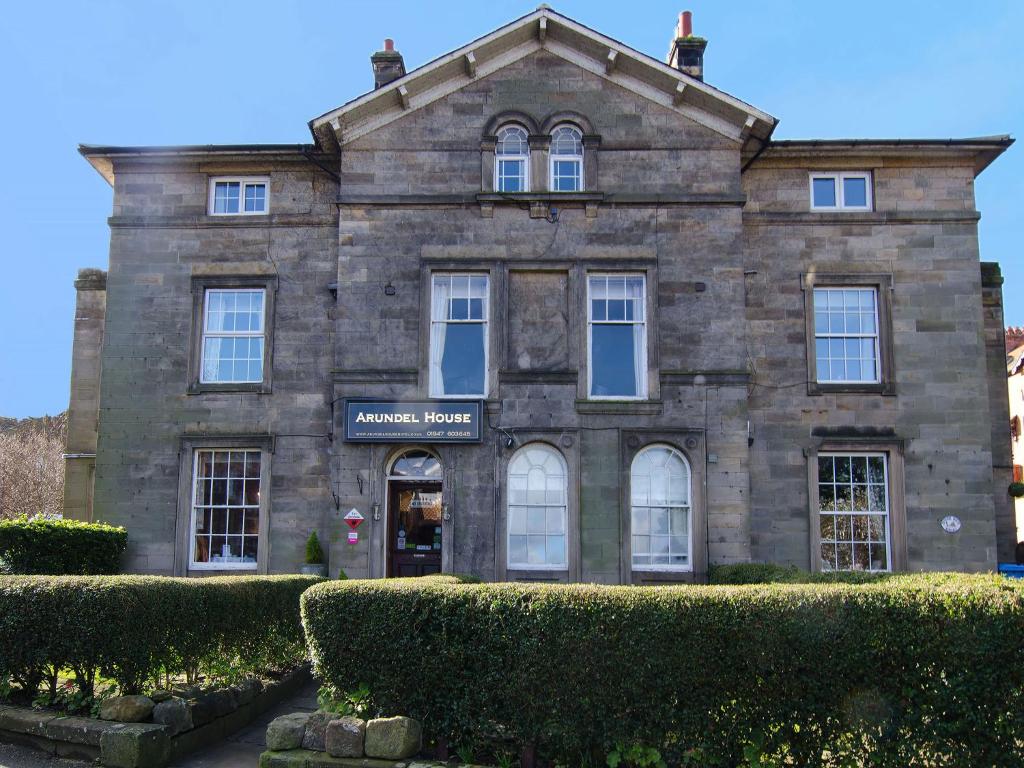 un vecchio edificio in pietra con cespugli di fronte di Arundel House a Whitby