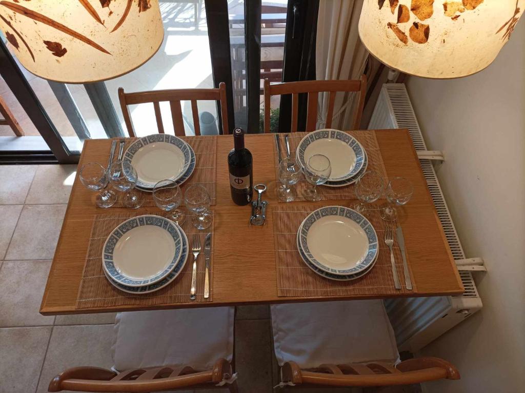 a table with plates and glasses and a bottle of wine at Breathe in Delphi - Spacious 3BR Apt with View in Delphi