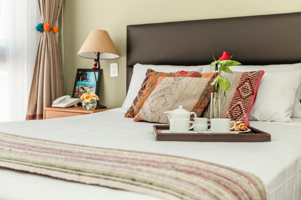 a bed with a tray with mugs and flowers on it at La Paz Apart Hotel in Lima