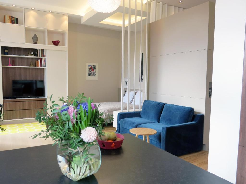 a living room with a blue couch and a vase with flowers at Design Marais Temple CityCosy in Paris