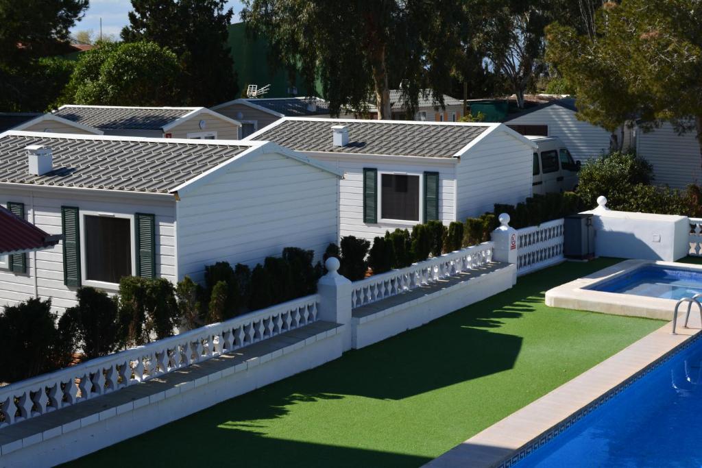 a house with a white fence and a swimming pool at Camping Valencia el Saler in El Saler