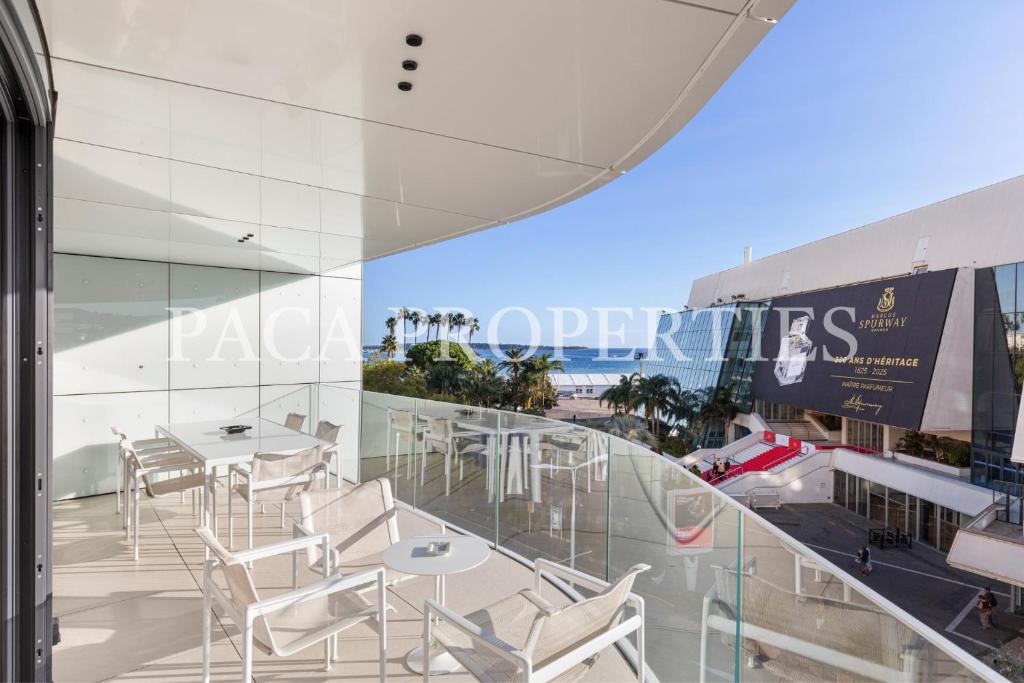 Il dispose d'un balcon avec des tables et des chaises blanches. dans l'établissement Paca Properties -401- 5 Chambres Luxe, à Cannes