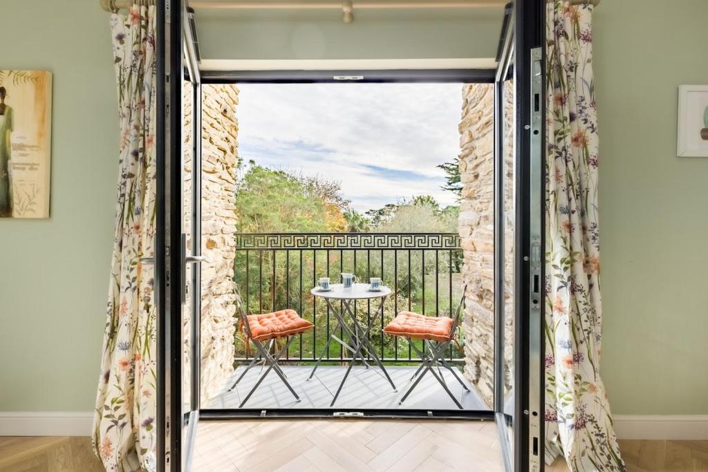 a room with a balcony with a table and chairs at Bream Loft, dog friendly, wood burner, walking distance to beach in Falmouth