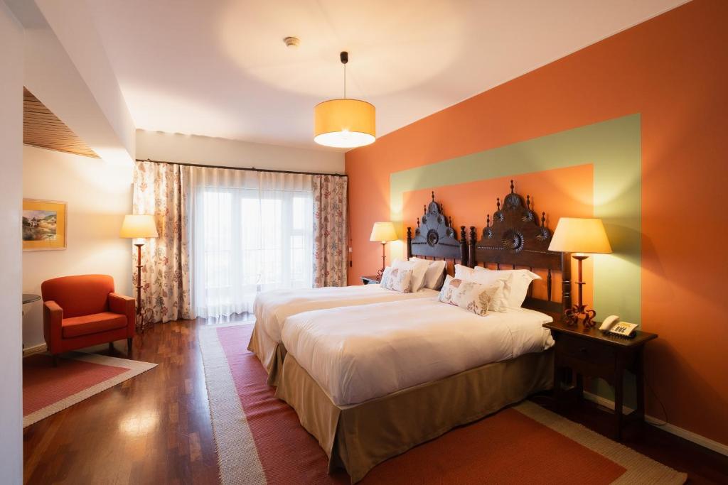 a hotel room with a large bed and a chair at Pousada de Valença in Valença