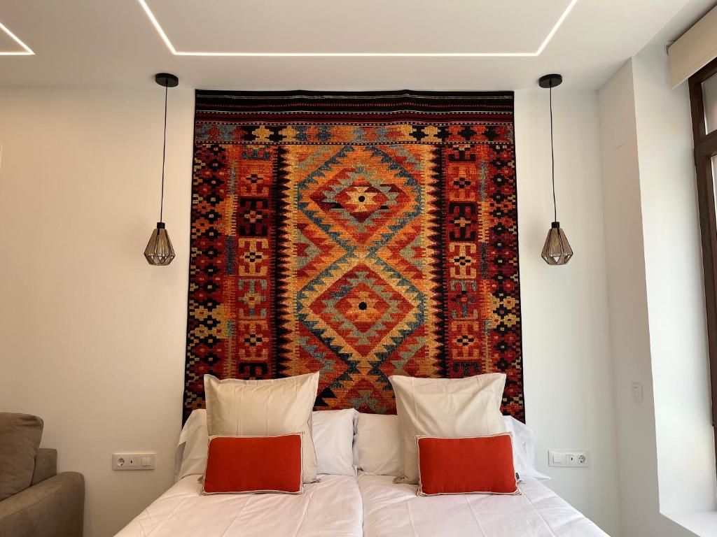 a tapestry hanging above a bed with two pillows at Apartments Vent de Vela in Valencia