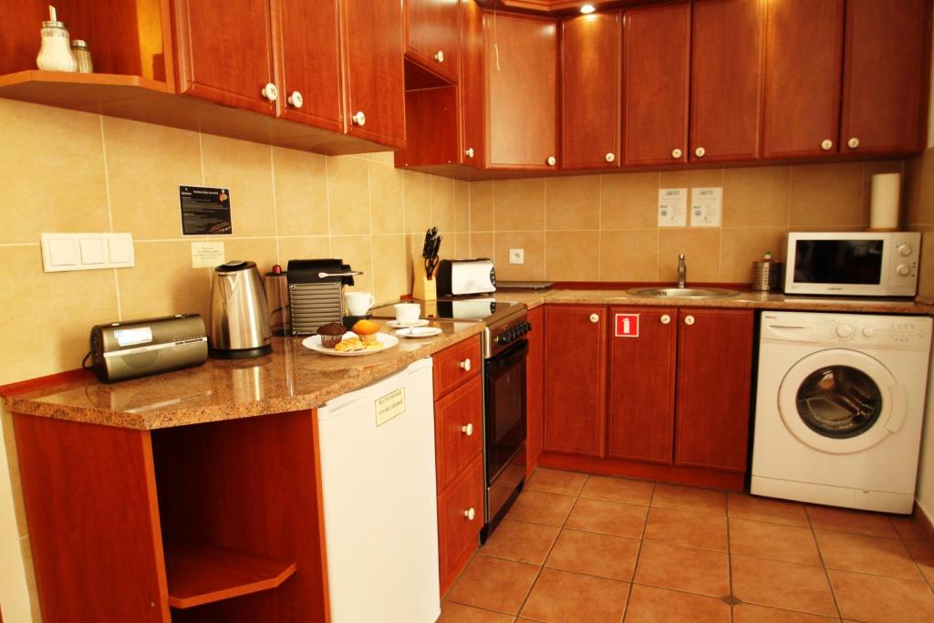 a kitchen with wooden cabinets and a washer and dryer at Ventus Rosa Apartments in Krakow
