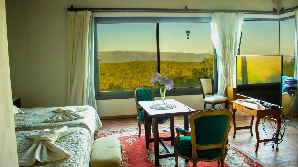 a living room with a table and a large window at Merlín Art Lodge in Atos Pampa