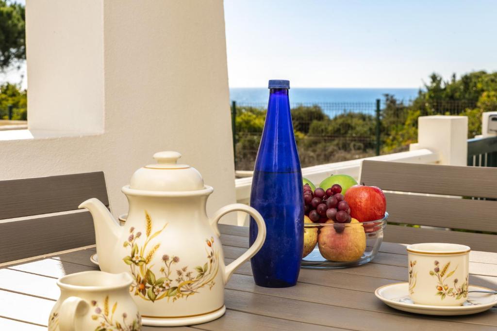 a table with a blue bottle and a bowl of fruit at 31 Terracos de Benagil - Casa Bobo in Benagil