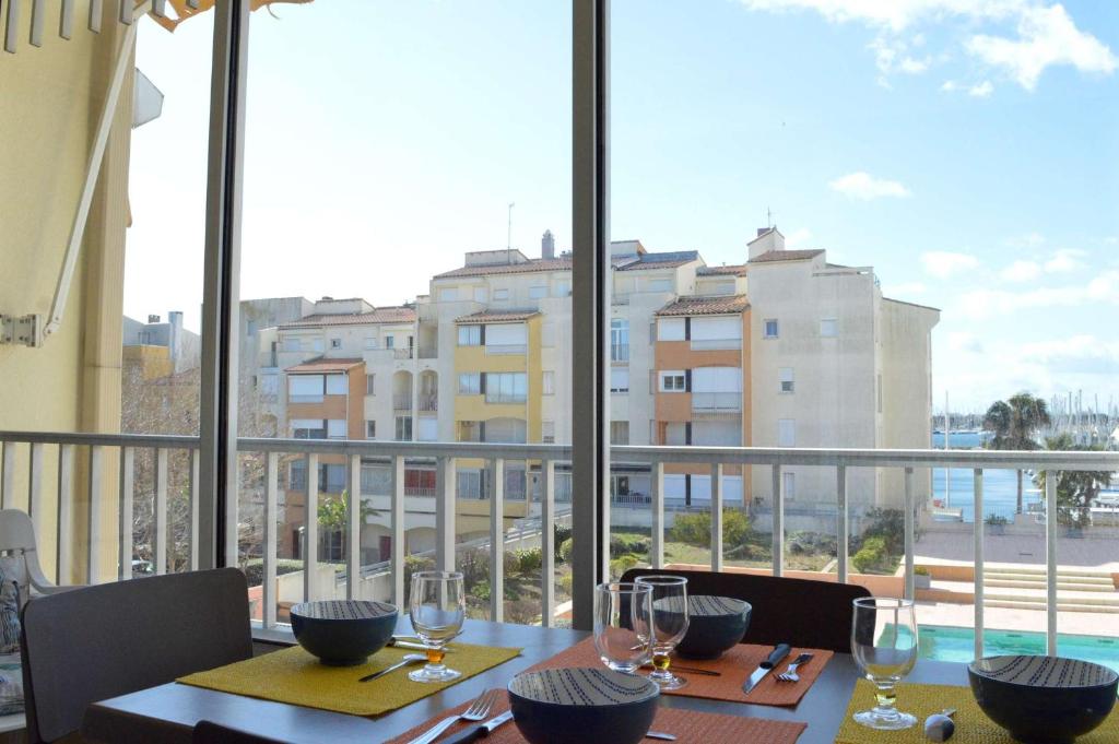 - une table avec des verres à vin et une vue sur un balcon dans l'établissement Appt 2 pièces cabine 6 couchages CAP D'AGDE CT100-010, au Cap d'Agde