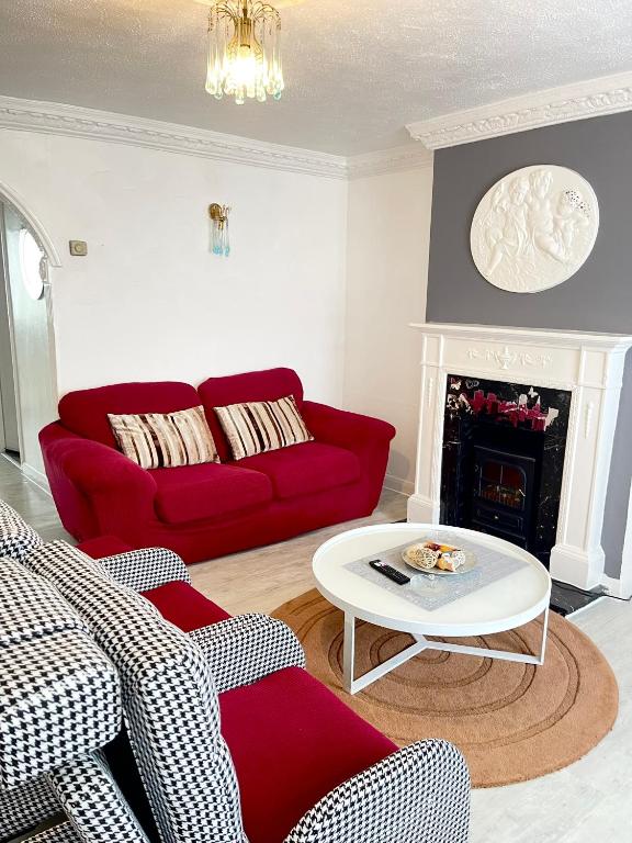 a living room with a red couch and a table at Shepherds House - 3 bedroom in Goodmayes