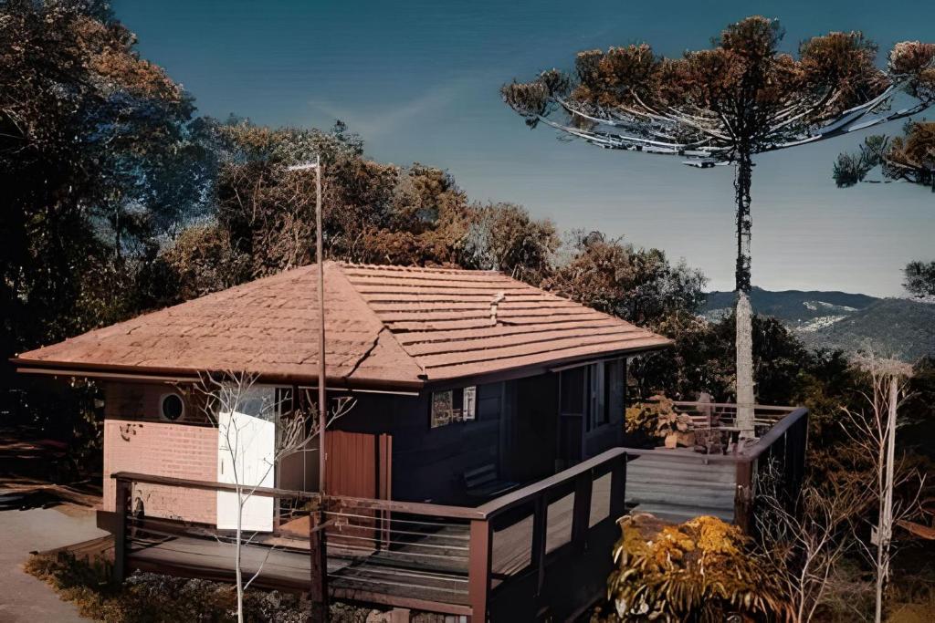 a small house with a brown roof on a deck at Casa do Sol, Charme e Conforto na Serra Velha in Campos do Jordão