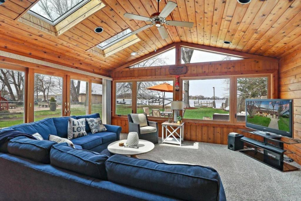 un soggiorno con un divano blu e una TV di Meyers Bay Sunset Lakefront Cottage in Fox Lake with Boat Pier a Fox Lake