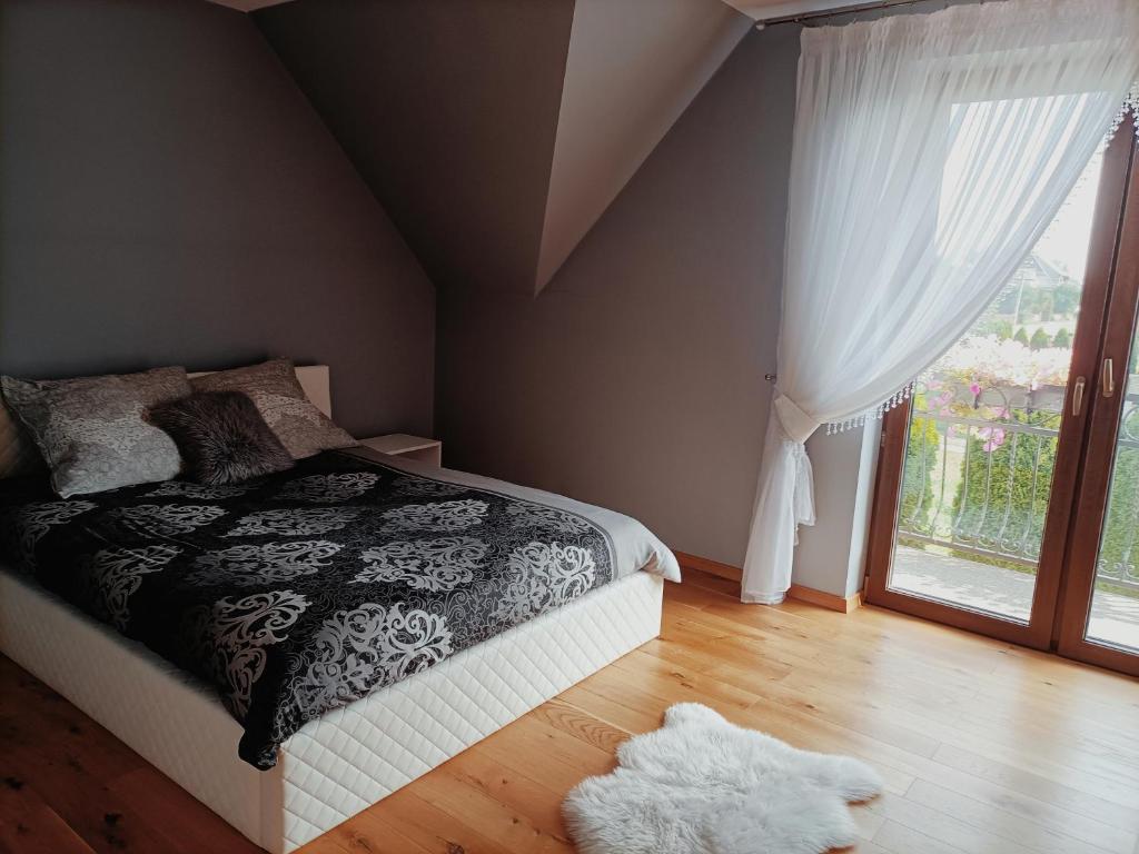 Un dormitorio con una cama y una ventana grande. en Przystań w Górach, en Lipnica Wielka