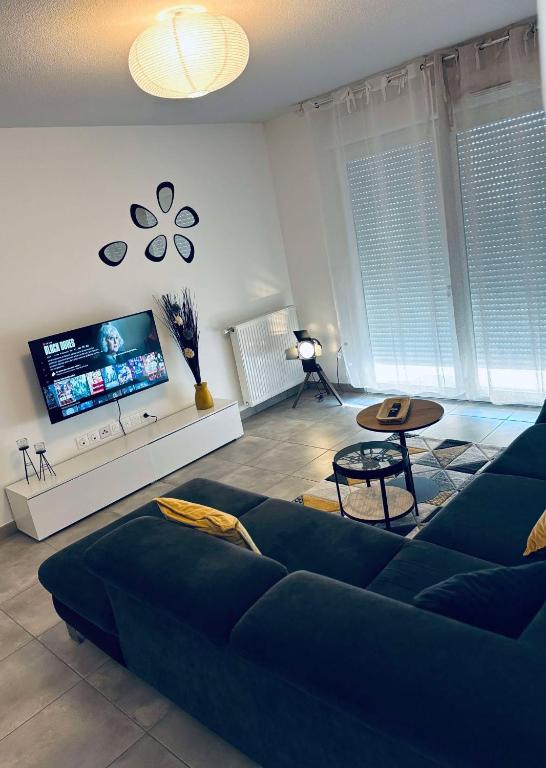 un salon avec un canapé bleu et une télévision dans l'établissement Cosy T3 Beauzelle proche MEETT, tram et aéroport, à Beauzelle