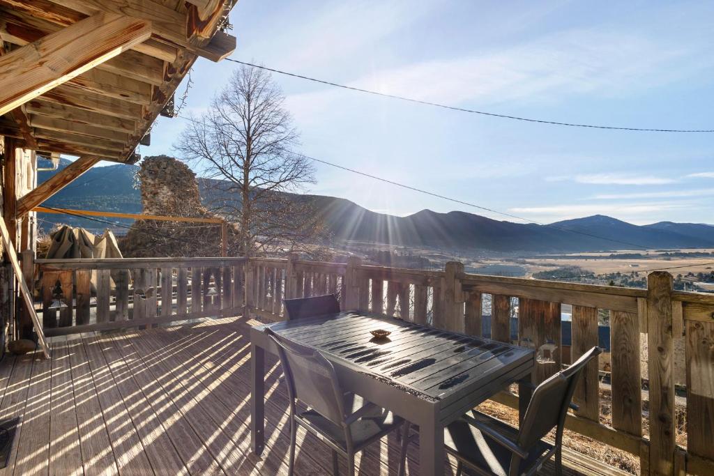 une terrasse en bois avec une table et des chaises dessus dans l'établissement Maison de village Puyvalador, à Puyvalador