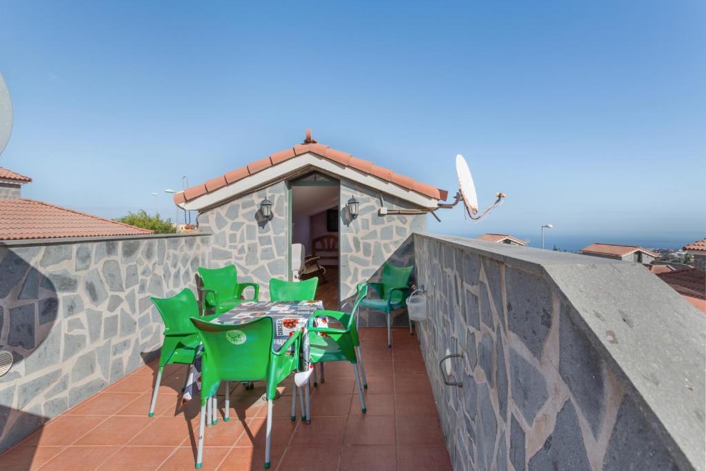 un patio con sillas verdes y una mesa en el balcón en Villa Doramas, en Firgas