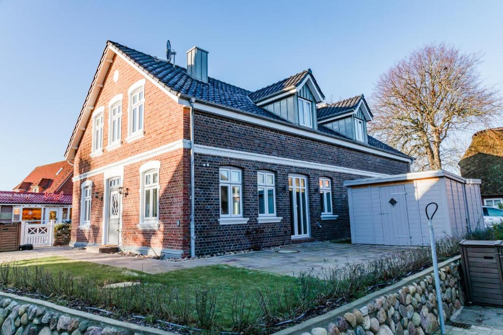 a red brick house with a white garage at Lokelk Lunhüs Hausteil 2 in Oevenum