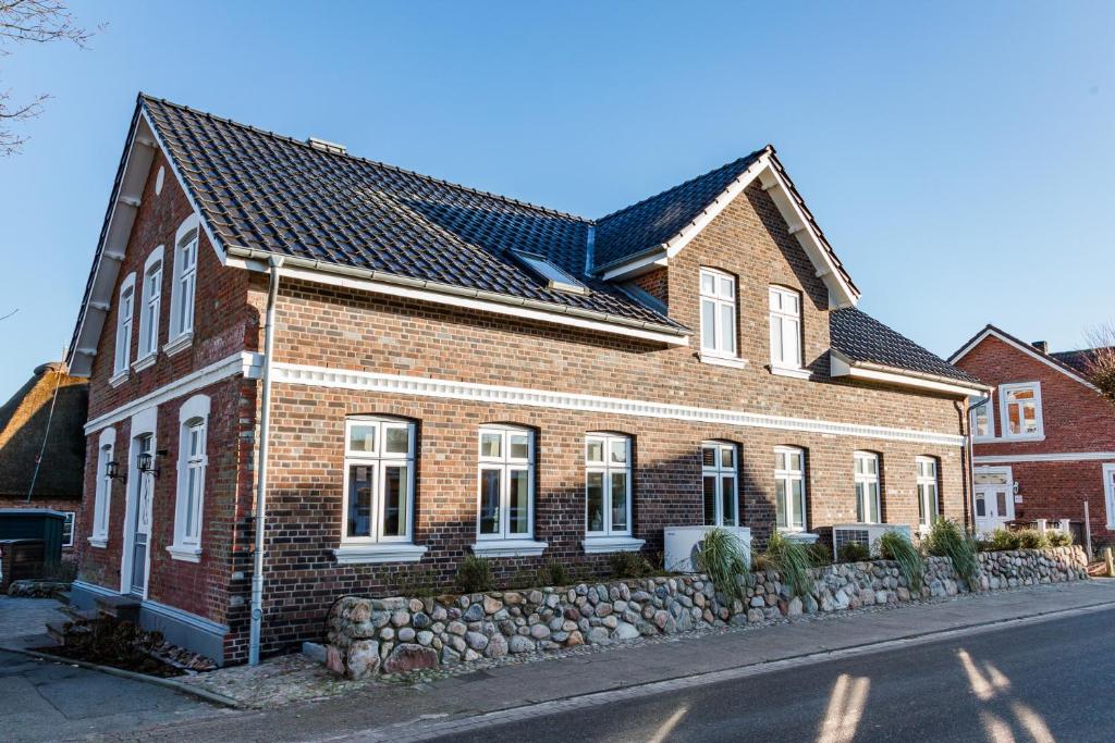 a brown brick house with a stone wall at Lokelk Lunhüs Hausteil 1 in Oevenum